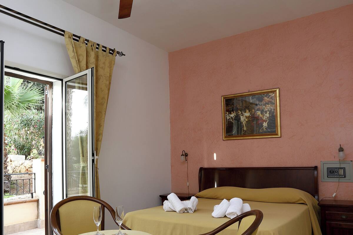 A hotel room with two beds, a table with a glass, and a chair.
