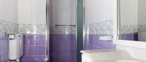 Un baño con inodoro, bidé y lavamanos, con azulejos morados y vigas de madera en el techo.