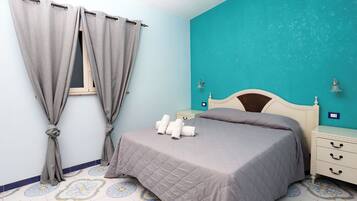 A bedroom with a bed, curtains, a nightstand, and a wall with a teal color.