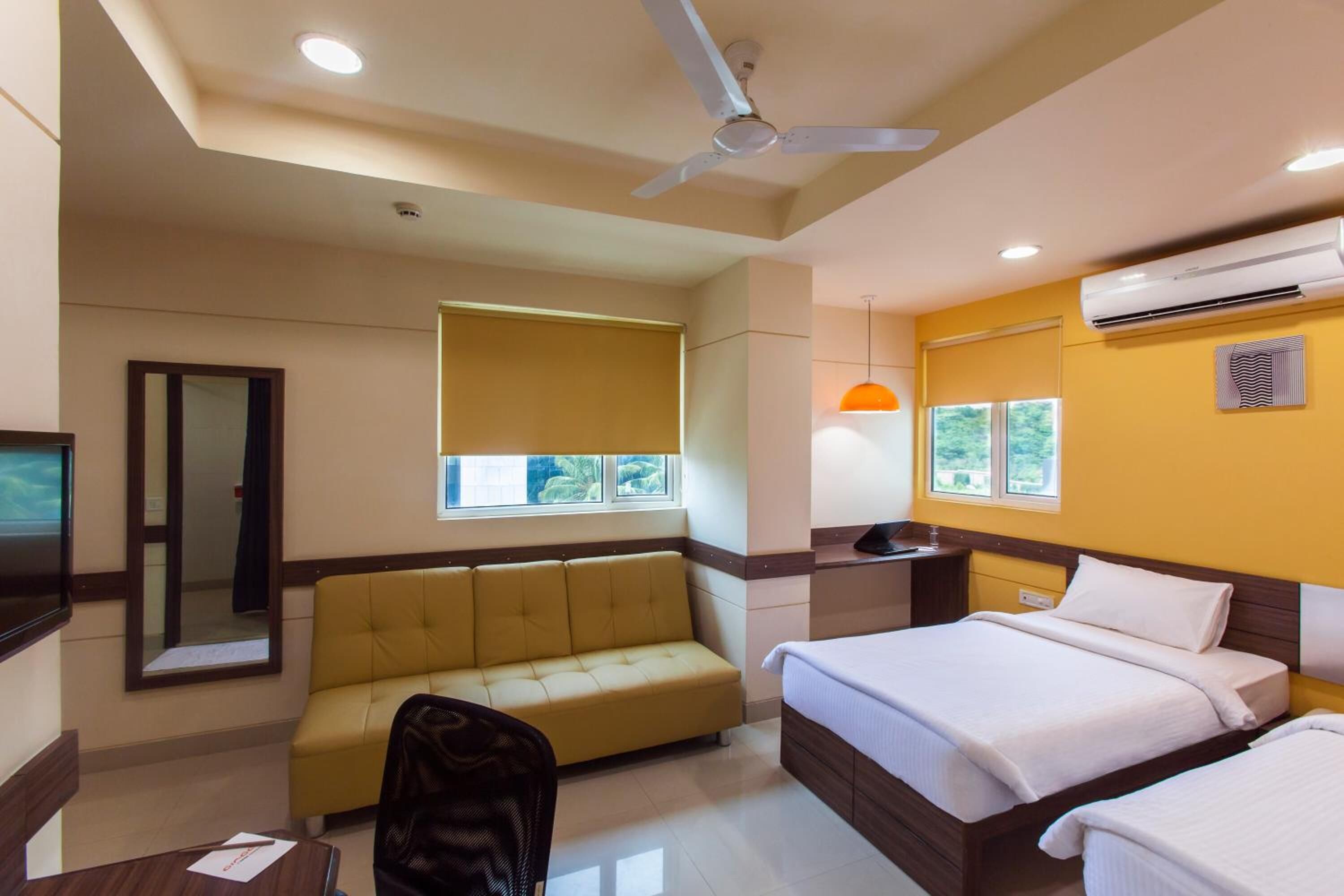 Una habitación de hotel con cama, sofá, escritorio y ventilador de techo.