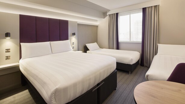Une chambre d’hôtel avec deux lits, un bureau et une chaise.