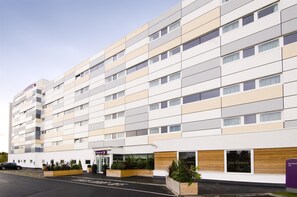 Un hotel de varios pisos con fachada moderna, un bar y bistró en la planta baja y un estacionamiento.