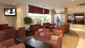 Un hall d’hôtel avec des sièges, un téléviseur et un comptoir d’accueil.