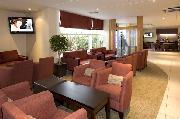 A hotel lobby with seating, a television, and a reception desk. - Premier Inn Manchester M56/J6 Runger Lane South (Altrincham)