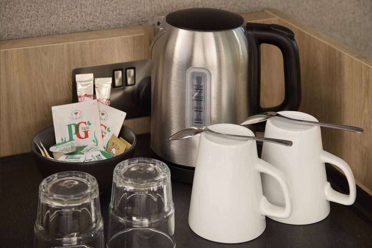 Un plan de travail de cuisine avec une bouilloire, des tasses et des sachets de thé PG Tips.
