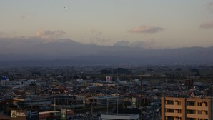 A cityscape with a mountain range in the background, buildings, and a road sign. - Aizuwakamatsu Washington Hotel (Aizuwakamatsu)