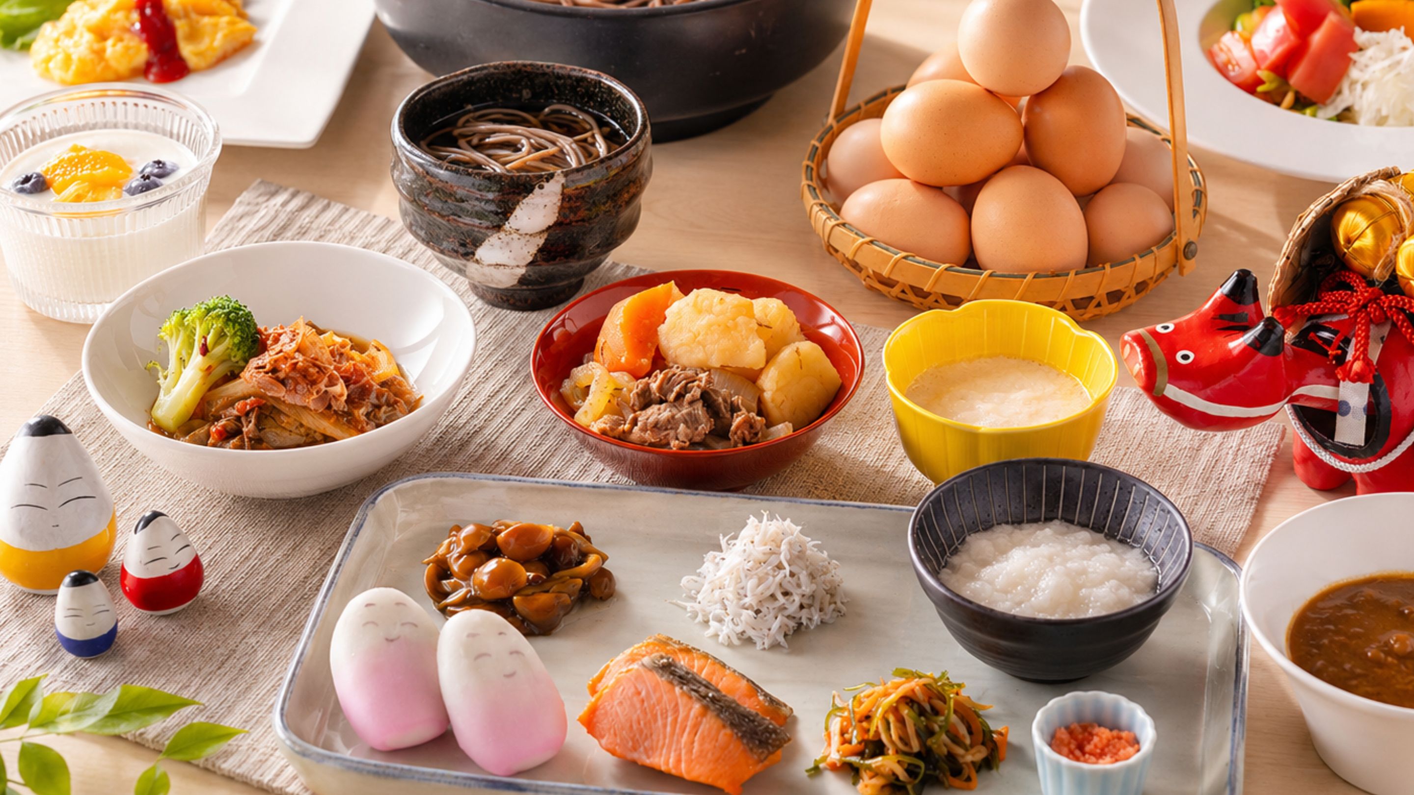 Variedad de platos y alimentos sobre una mesa, incluyendo tazones de sopa, un plato de salmón y una cesta de huevos.