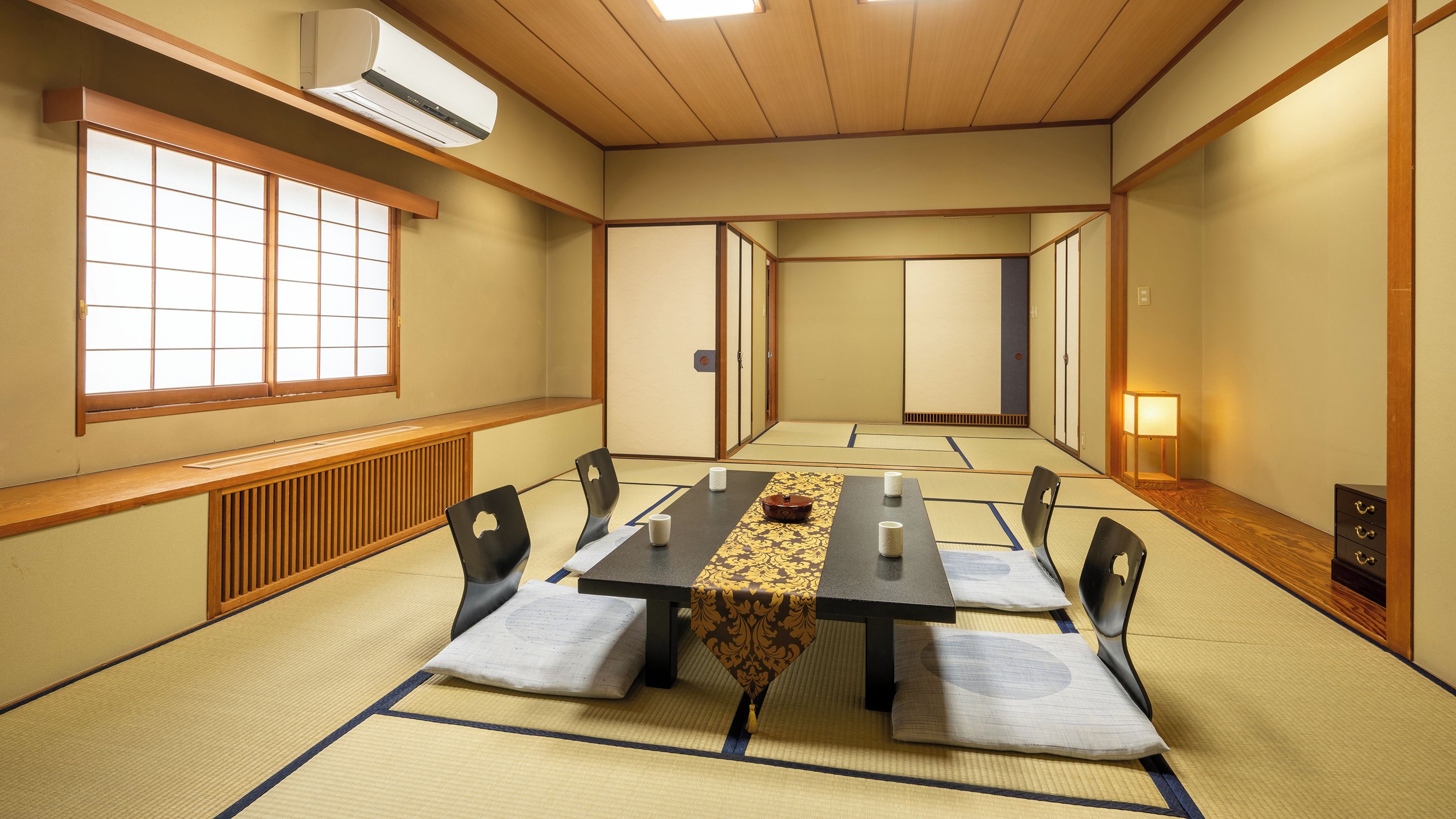 Ein traditioneller japanischer Raum mit Tatami-Böden, einem niedrigen Tisch mit Kissen und Schiebetüren.