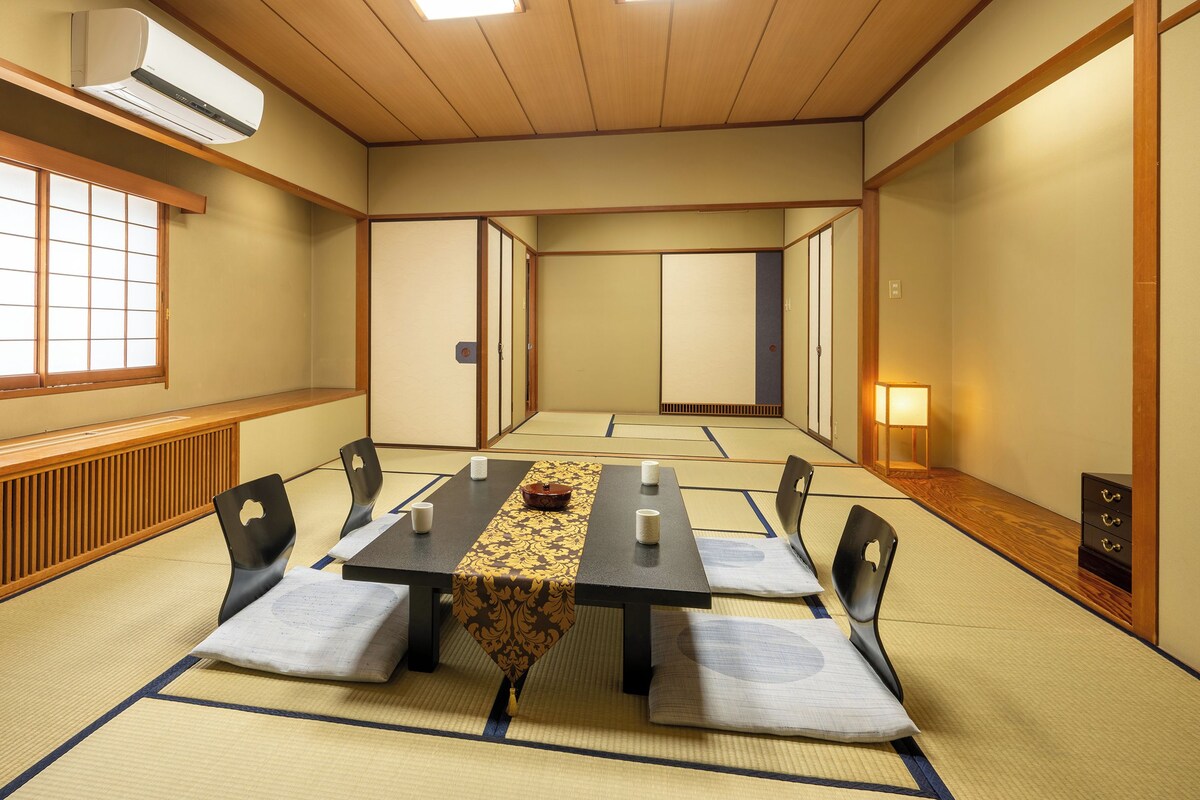 Una tradizionale stanza giapponese con pavimento in tatami, un tavolino con cuscini e porte scorrevoli.
