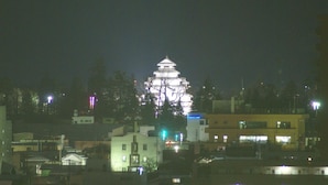 A traditional Japanese building with multiple tiers and a pagoda-style roof, surrounded by modern buildings and streetlights. - Aizuwakamatsu Washington Hotel (Aizuwakamatsu)
