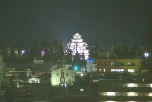 Un edificio tradizionale giapponese con più livelli e un tetto a pagoda, circondato da edifici moderni e lampioni.