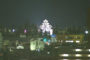 Un edificio japonés tradicional con varios niveles y un tejado al estilo pagoda, rodeado de edificios modernos y farolas.
