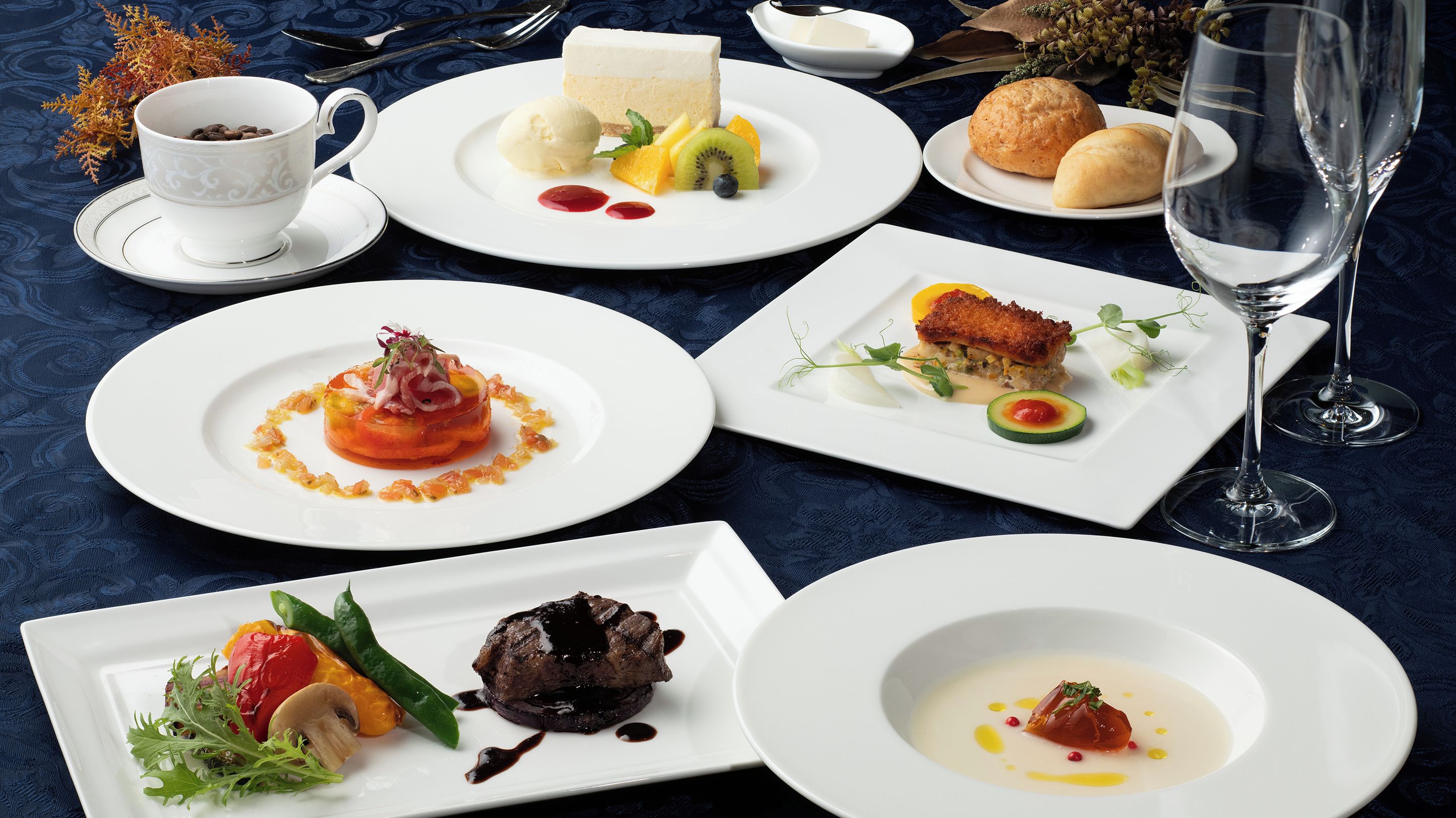 Une table dressée avec différents plats, notamment un gâteau au fromage, des fruits et un dessert aux baies.