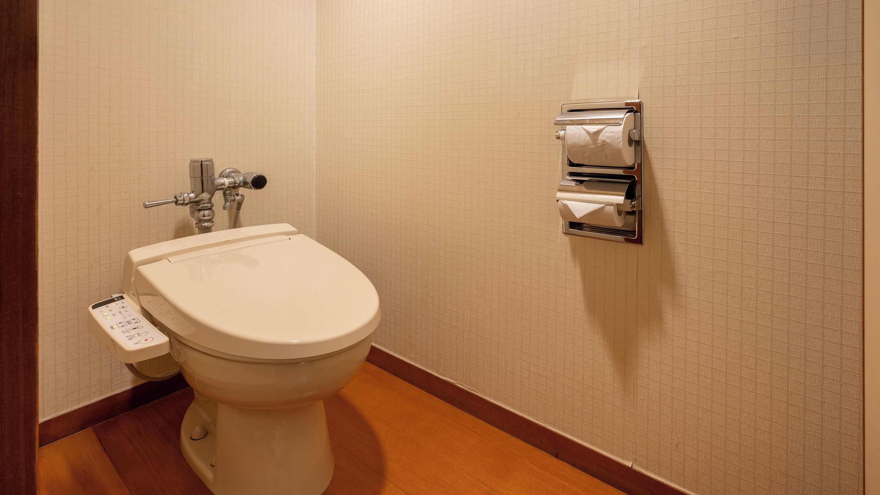 Een moderne badkamer met een toilet, een handdroger en een papieren handdoekdispenser.