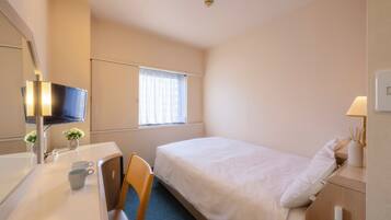 A hotel room with a bed, a desk, a chair, a television, and a window with curtains.