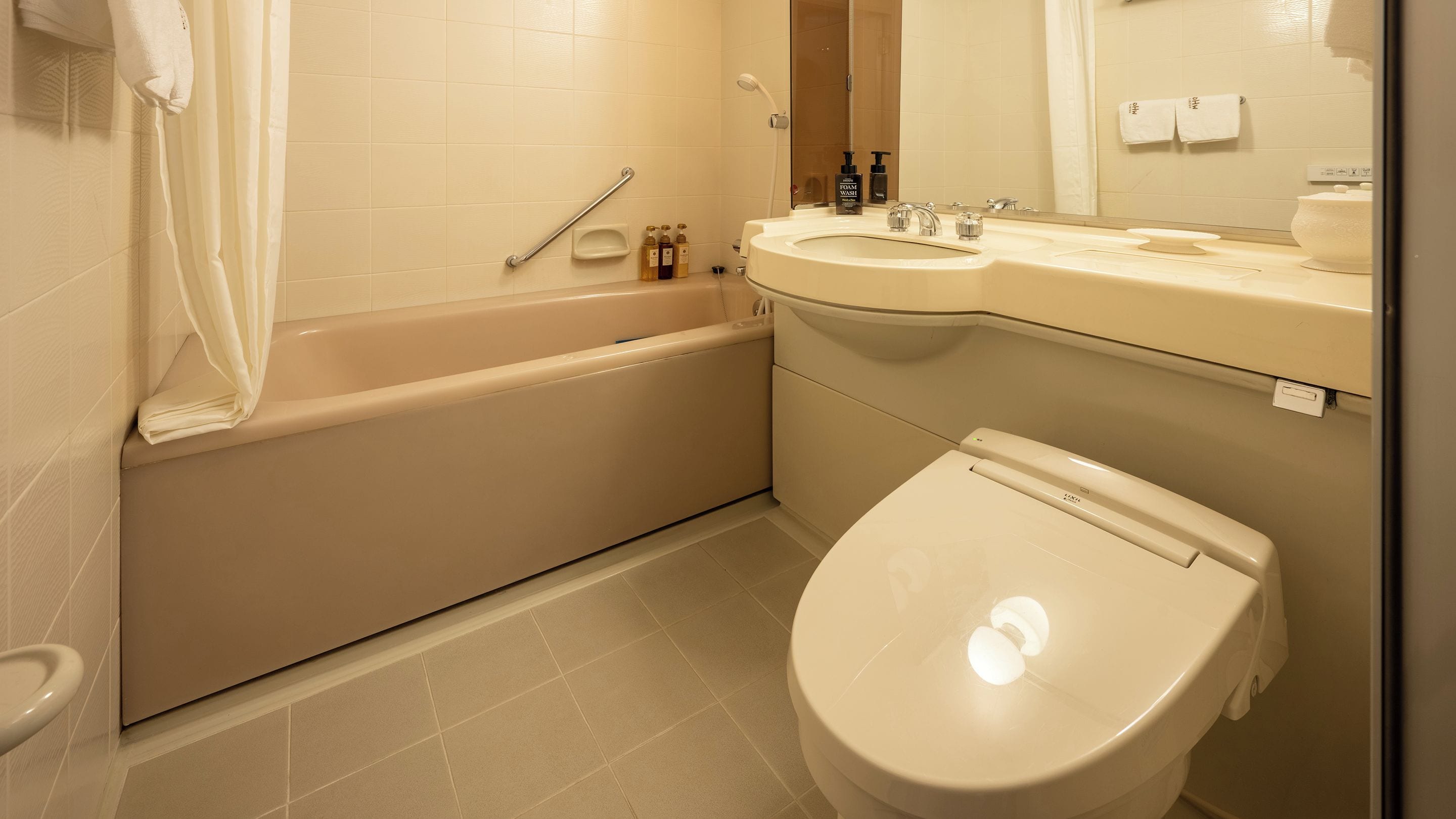 A bathroom with a bathtub, toilet, sink, and a mirror.