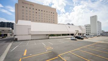 A hotel with a modern design, featuring a large parking lot and multiple vehicles.