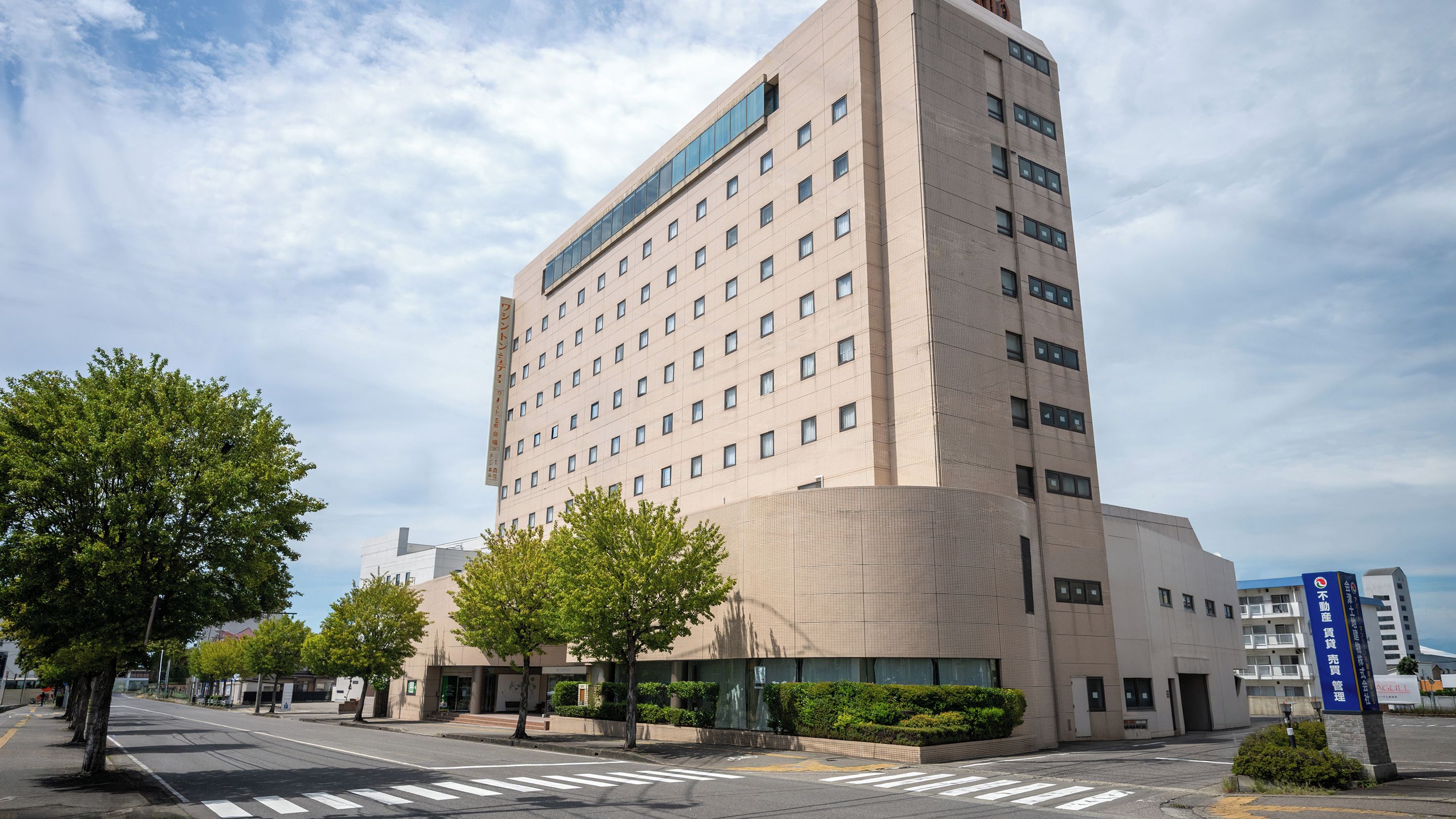 A multi-story hotel with a modern architectural design, featuring a prominent entrance and a clear sky.