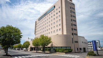 A multi-story hotel with a modern architectural design, featuring a prominent entrance and a clear sky.
