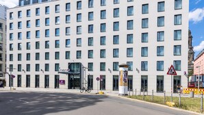 Un hôtel à plusieurs étages, doté d’une façade uniforme, de grandes fenêtres et d’une entrée imposante.
