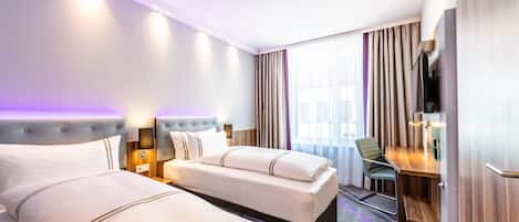 Habitación de hotel con dos camas, un escritorio, una silla, televisión y un amplio ventanal con cortinas.