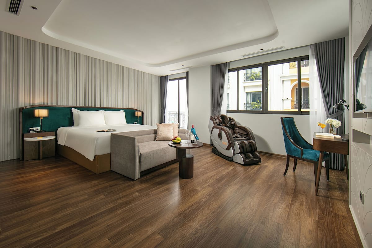 Une chambre d’hôtel moderne dotée d’un grand lit, d’un coin salon avec une table basse, d’un tapis de course et d’une table à manger avec des chaises.