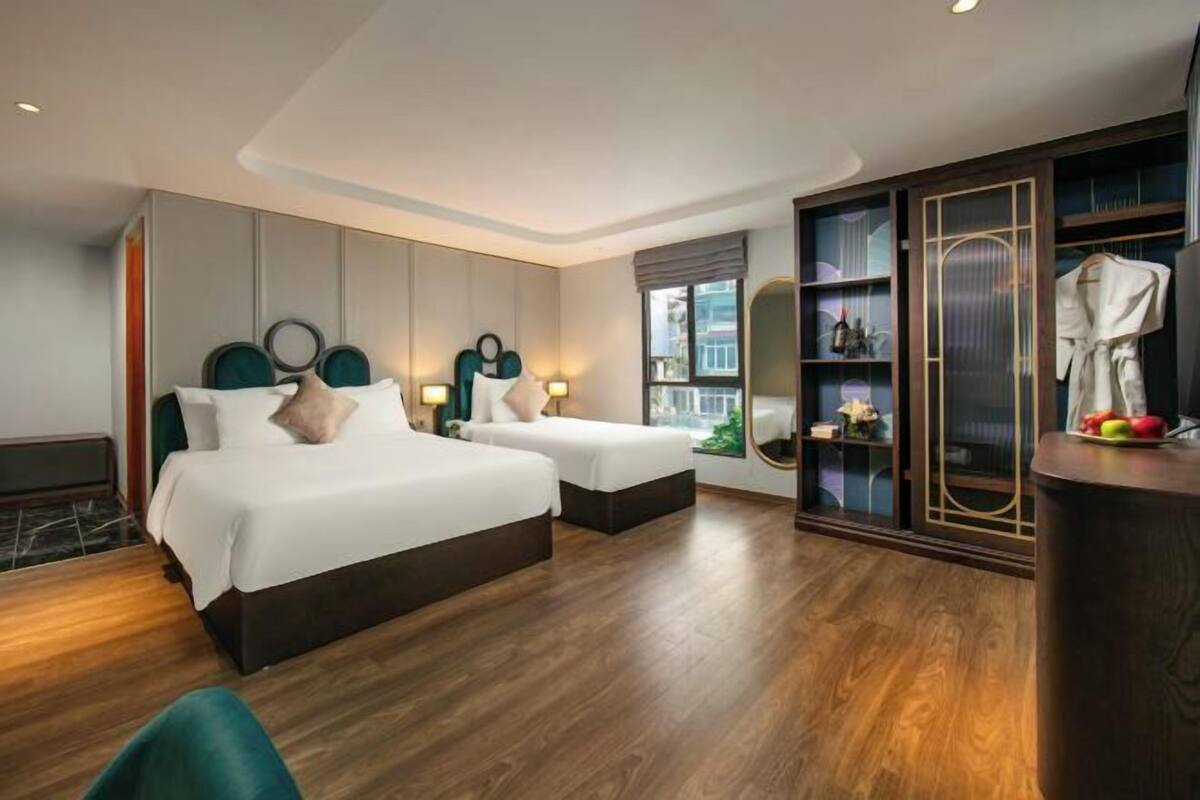 Une chambre d’hôtel avec deux lits, une armoire, un miroir et une fenêtre.
