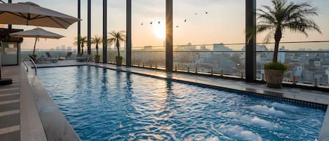 Alberca techada, alberca al aire libre y sombrillas en la alberca