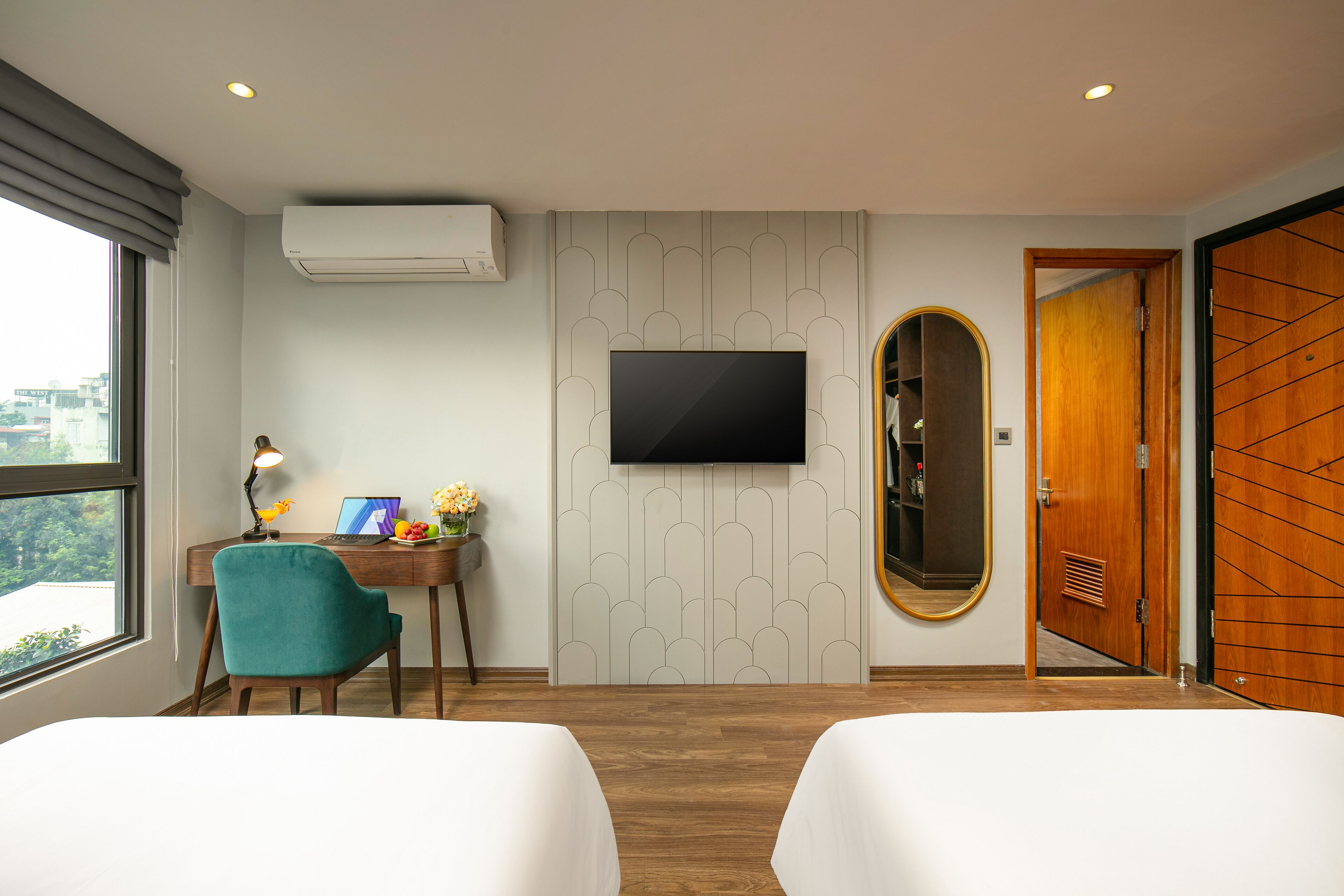 A hotel room with a desk, two beds, a TV, a mirror, and a wardrobe.
