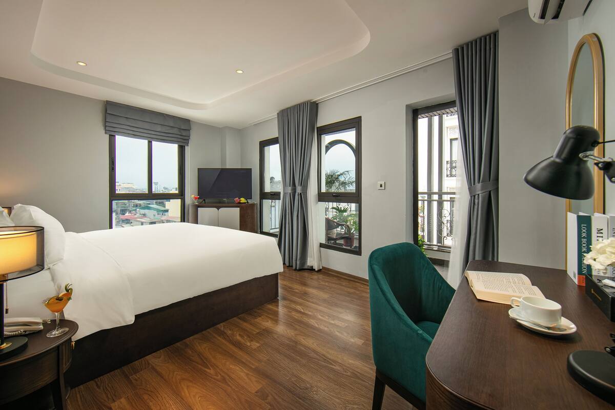 Une chambre d’hôtel avec un grand lit, un bureau avec une chaise, une télévision et une vue sur la ville.
