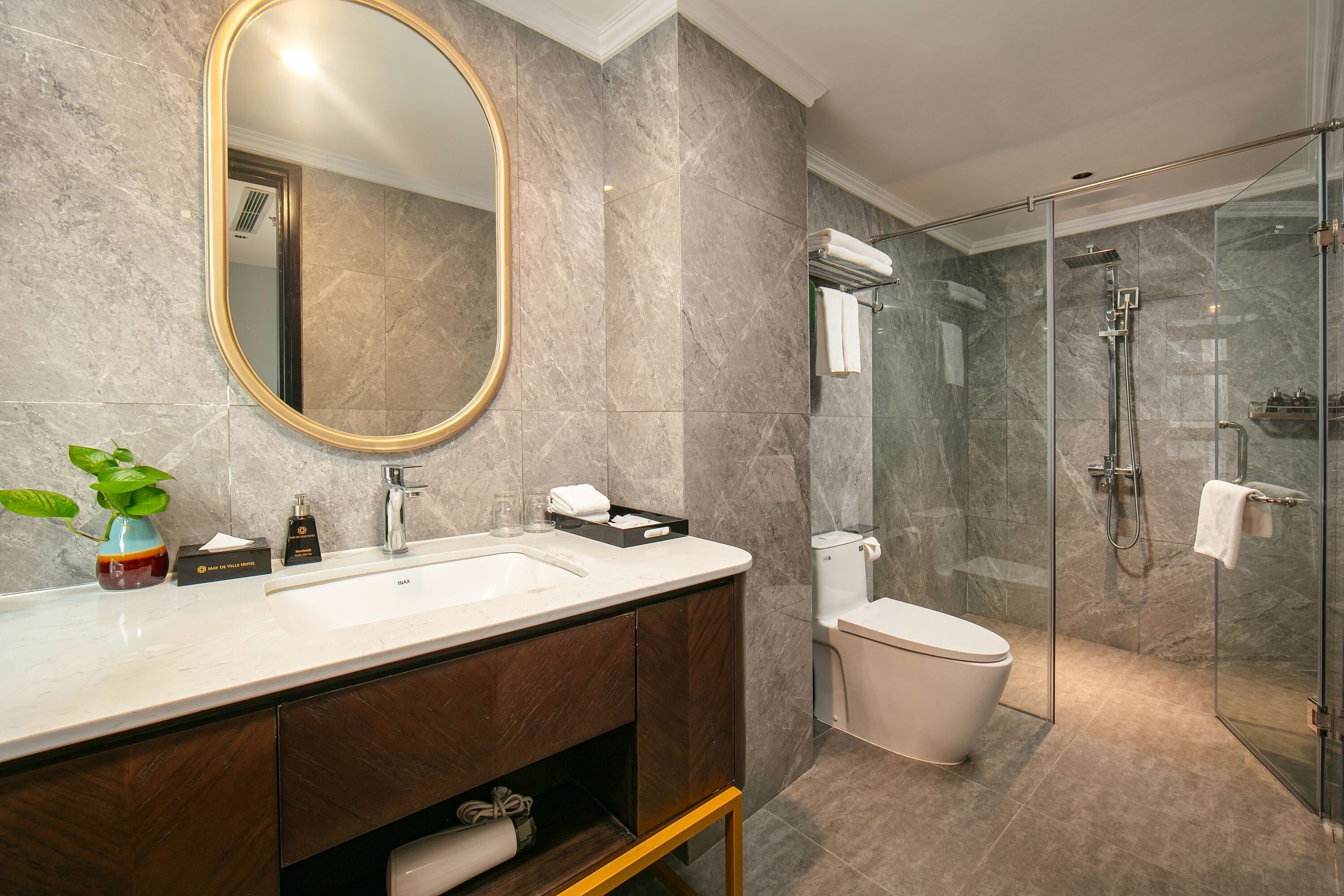 Un baño moderno con un espejo grande, un lavamanos, un inodoro y una ducha con cerramiento de vidrio.