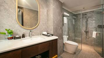 Un baño moderno con un espejo grande, un lavamanos, un inodoro y una ducha con cerramiento de vidrio.