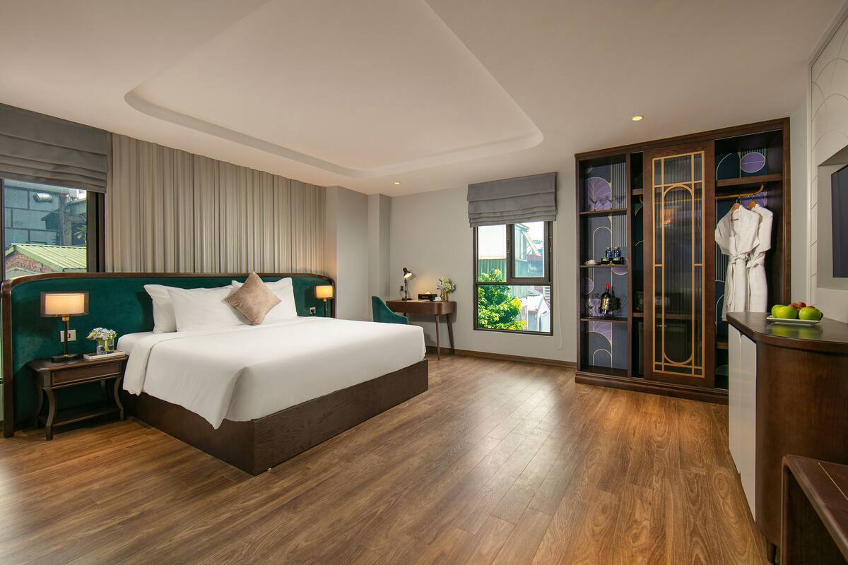 Une chambre d’hôtel avec un grand lit, un bureau, une armoire et une vue sur la verdure.