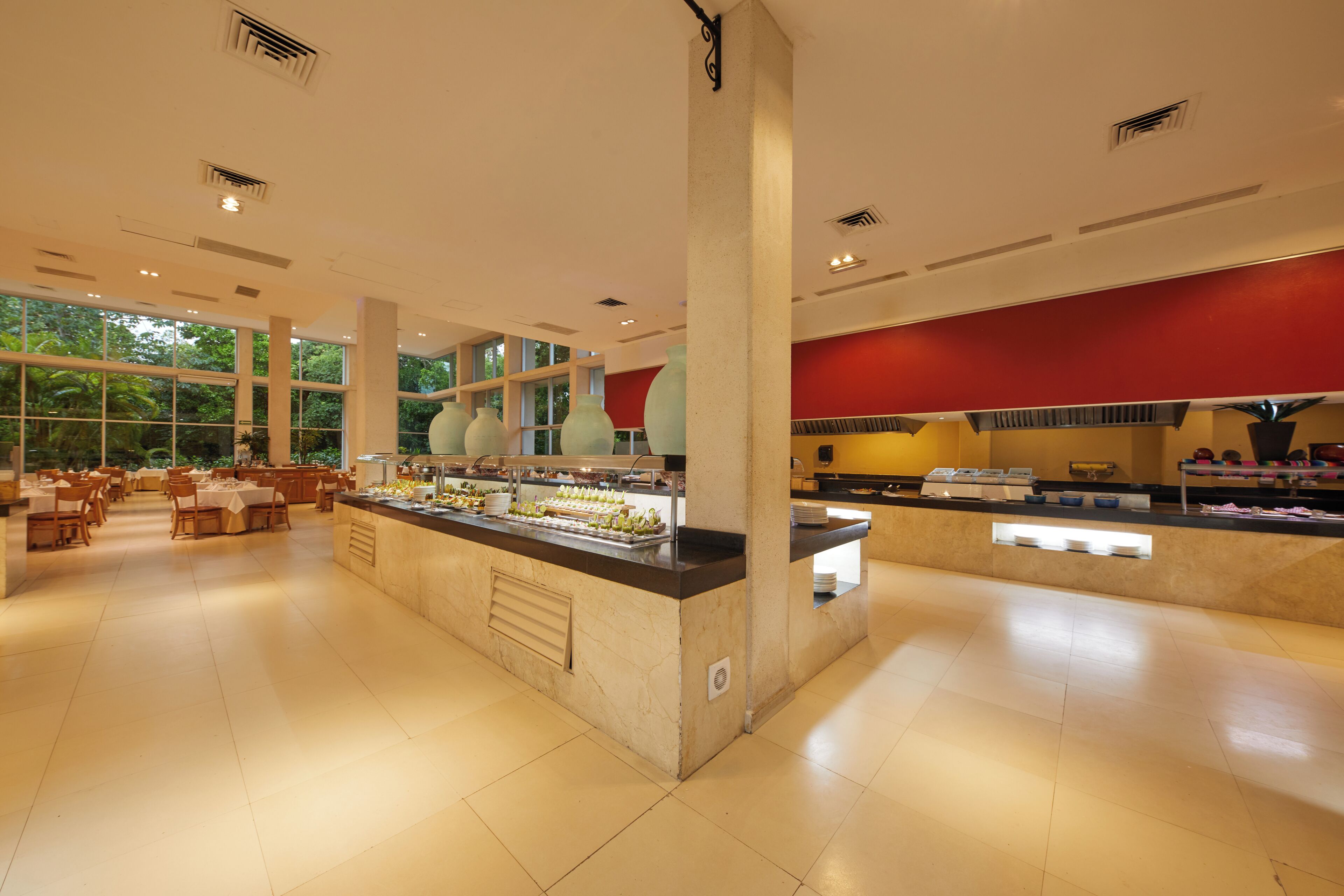 A spacious buffet area with multiple food stations, a central serving counter, and a dining area with tables and chairs.
