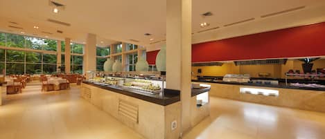 A spacious buffet area with multiple food stations, a central serving counter, and a dining area with tables and chairs.
