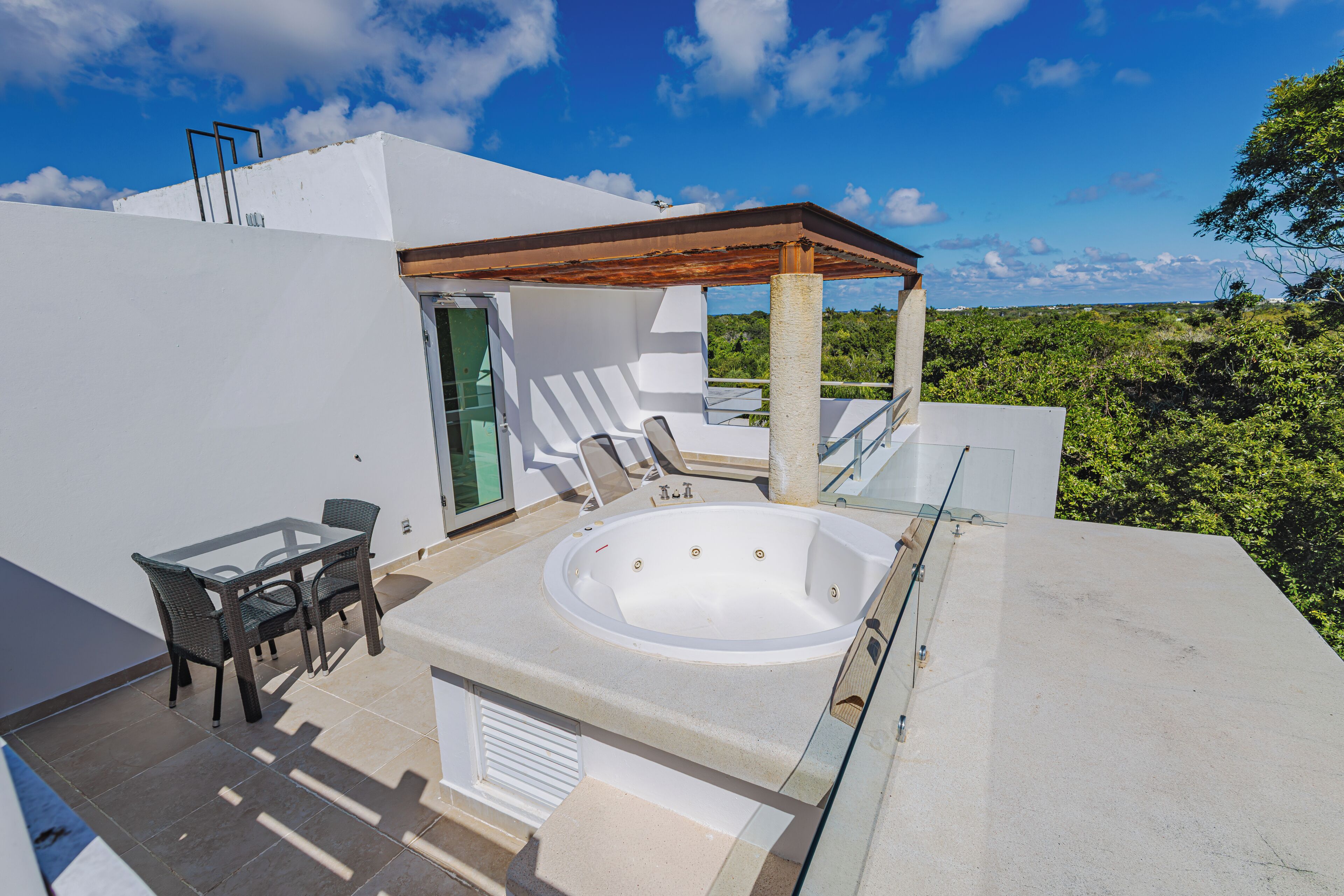 Una terraza en la azotea con jacuzzi, zona de estar y pérgola.