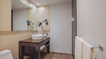 Une salle de bain équipée d’un lavabo, d’un miroir, d’un sèche-cheveux et d’un porte-serviettes.
