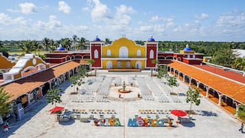 A large courtyard with a central fountain, surrounded by seating areas and a prominent building with domes.