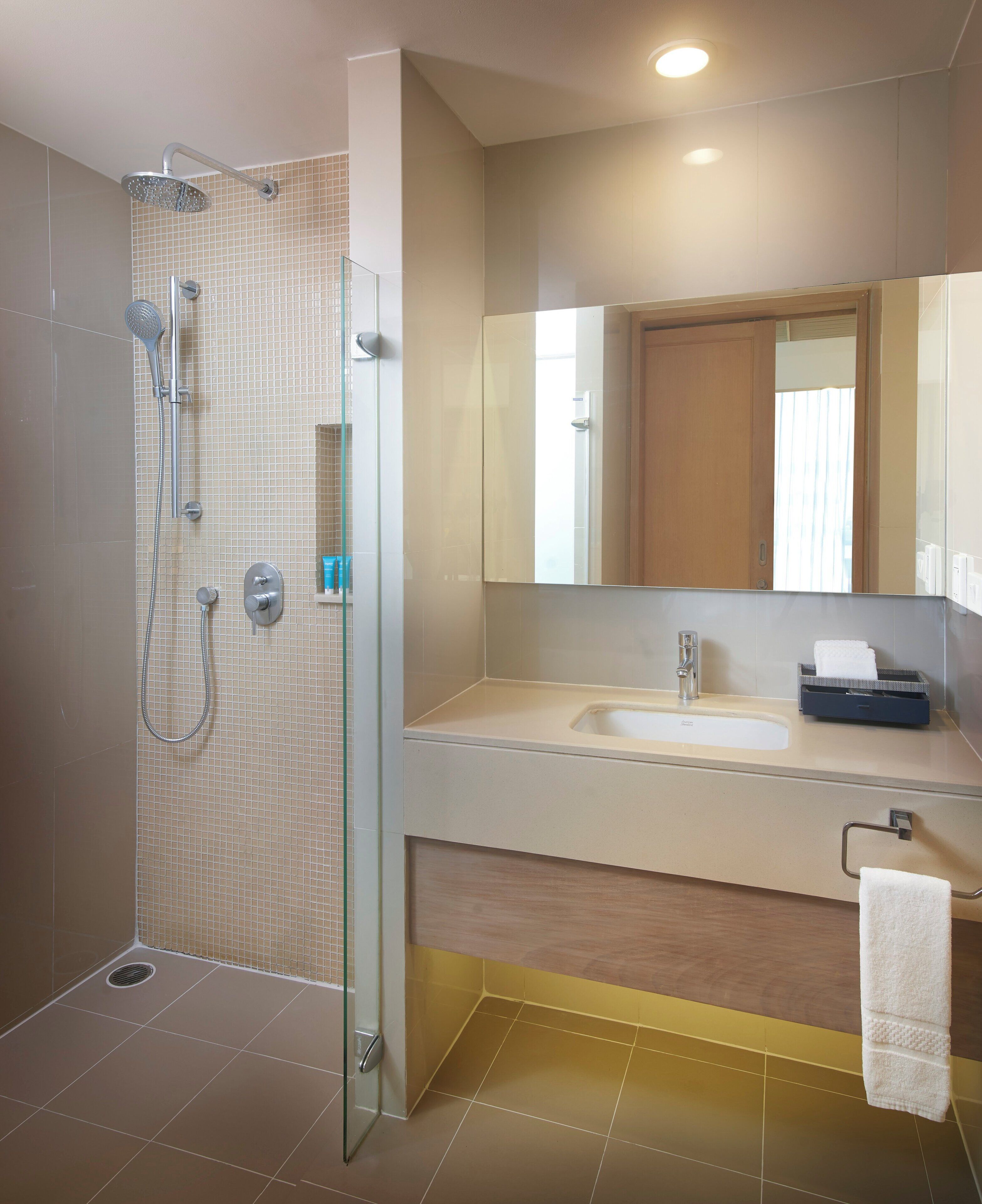 A modern bathroom with a glass-enclosed shower, a sink, and a mirror.