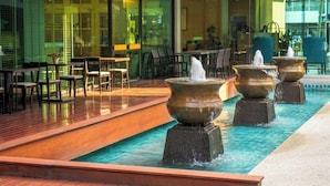 Zona de piscina exterior moderna con mobiliario de terraza de madera y tres fuentes.