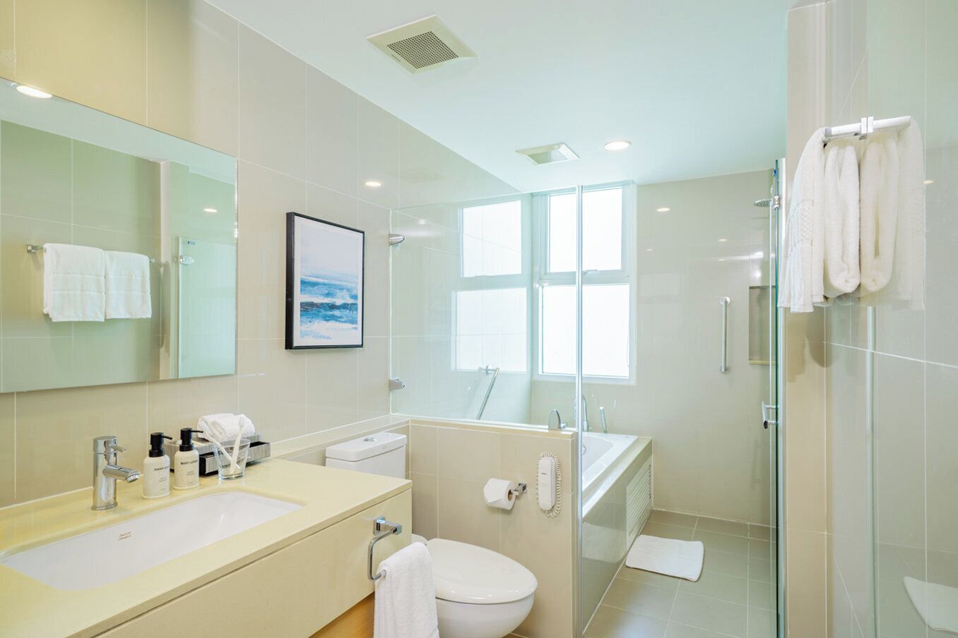 A modern bathroom with a large mirror, a sink, a toilet, and a glass-enclosed shower area.