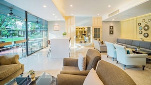 Amplia sala de estar con pared de vidrio, una mesa blanca en el centro y un conjunto de sofás y sillones.