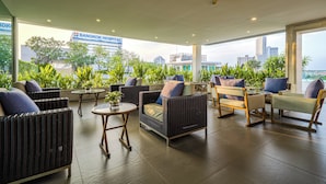 Una zona de estar exterior moderna con mobiliario de mimbre y vistas a la ciudad.
