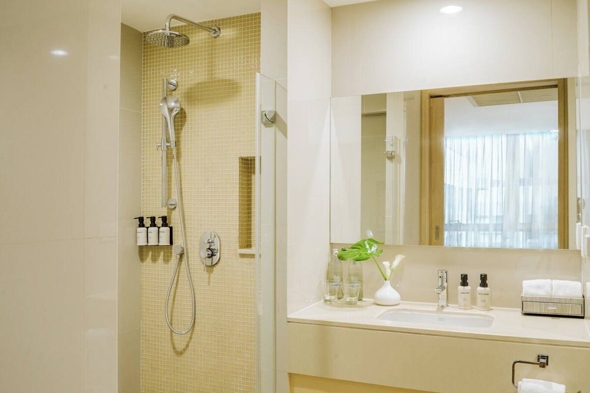 Une salle de bain moderne équipée d’une douche, d’un lavabo avec des articles de toilette et d’un miroir.