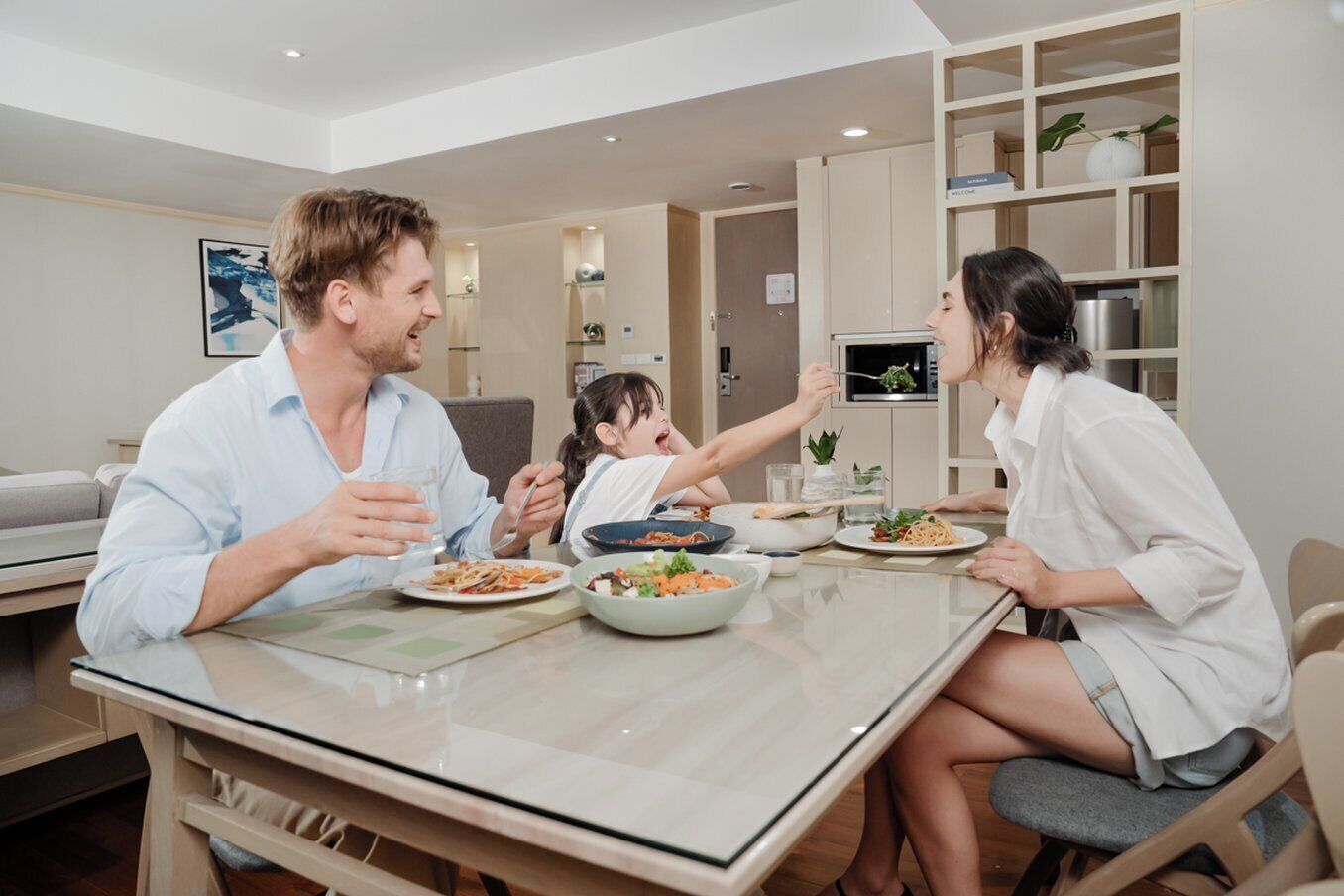 Una familia cenando en una cocina moderna con mesa, sillas y horno empotrado.