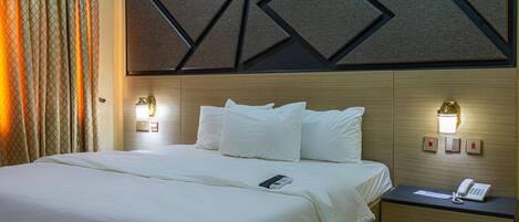 A hotel room with a bed, bedside table, and wall-mounted light fixtures.
