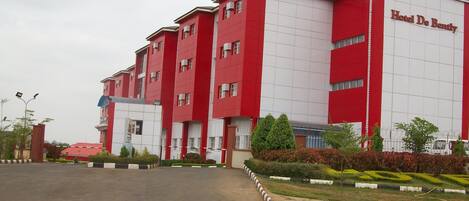 A multi-story building with a red and white facade, labeled "Hotel De Bendy."