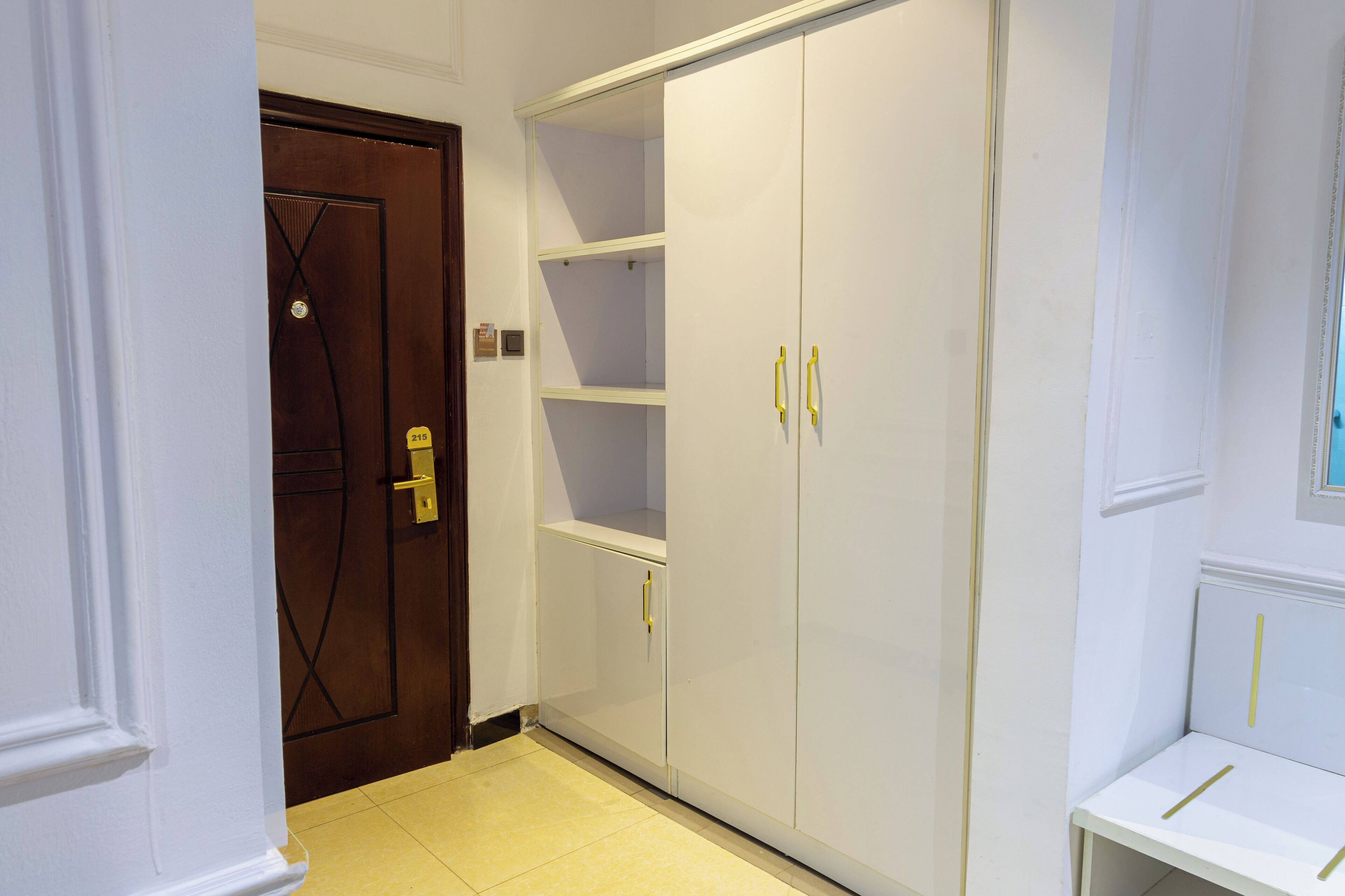A hallway with a white wardrobe, a brown door, and a white table.