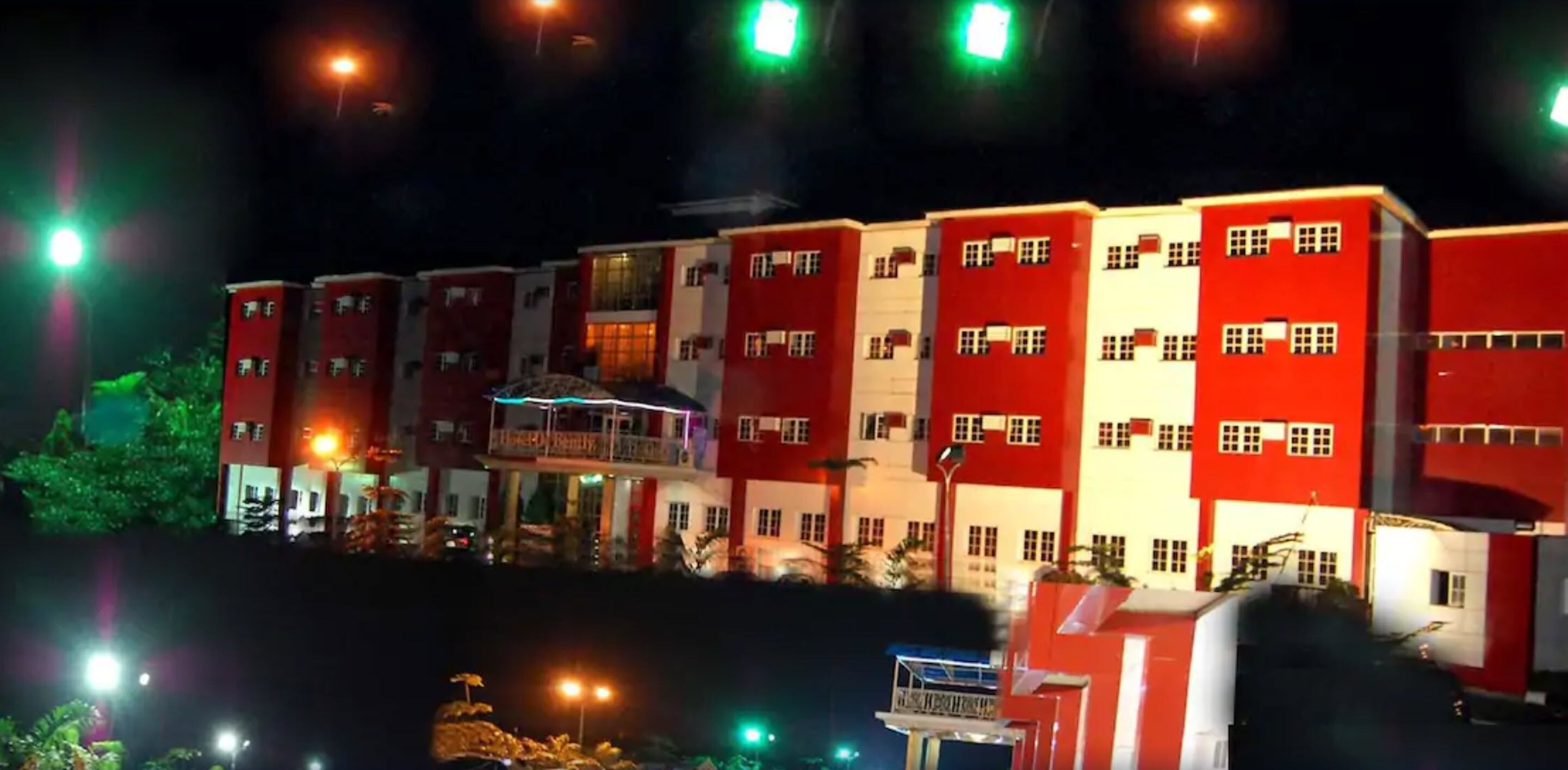 Un hotel de varios pisos con fachada roja y blanca, múltiples balcones y exterior bien iluminado.