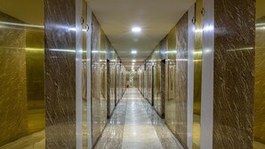 A long, narrow hallway with reflective walls and a shiny floor, leading to a distant exit. - Hotel De Bently (Abuja)
